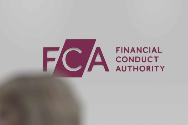 The logo of FCA Financial Conduct Authority on a white wall, in the foreground a blurry passerby.